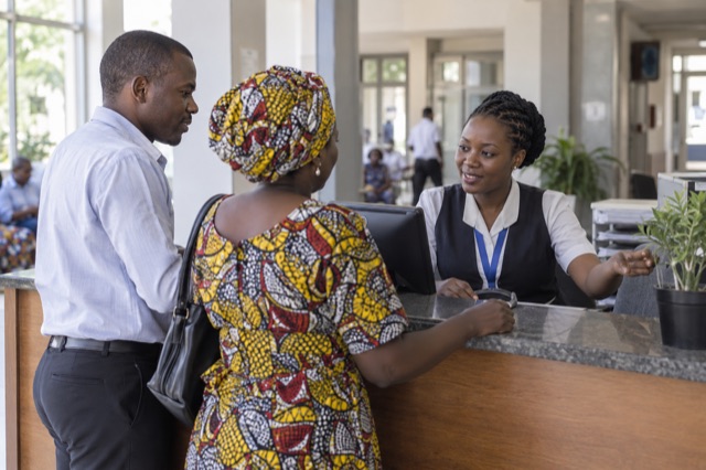 Illustration d’une agente d’accueil orientant des visiteurs dans un hôpital en RDC.